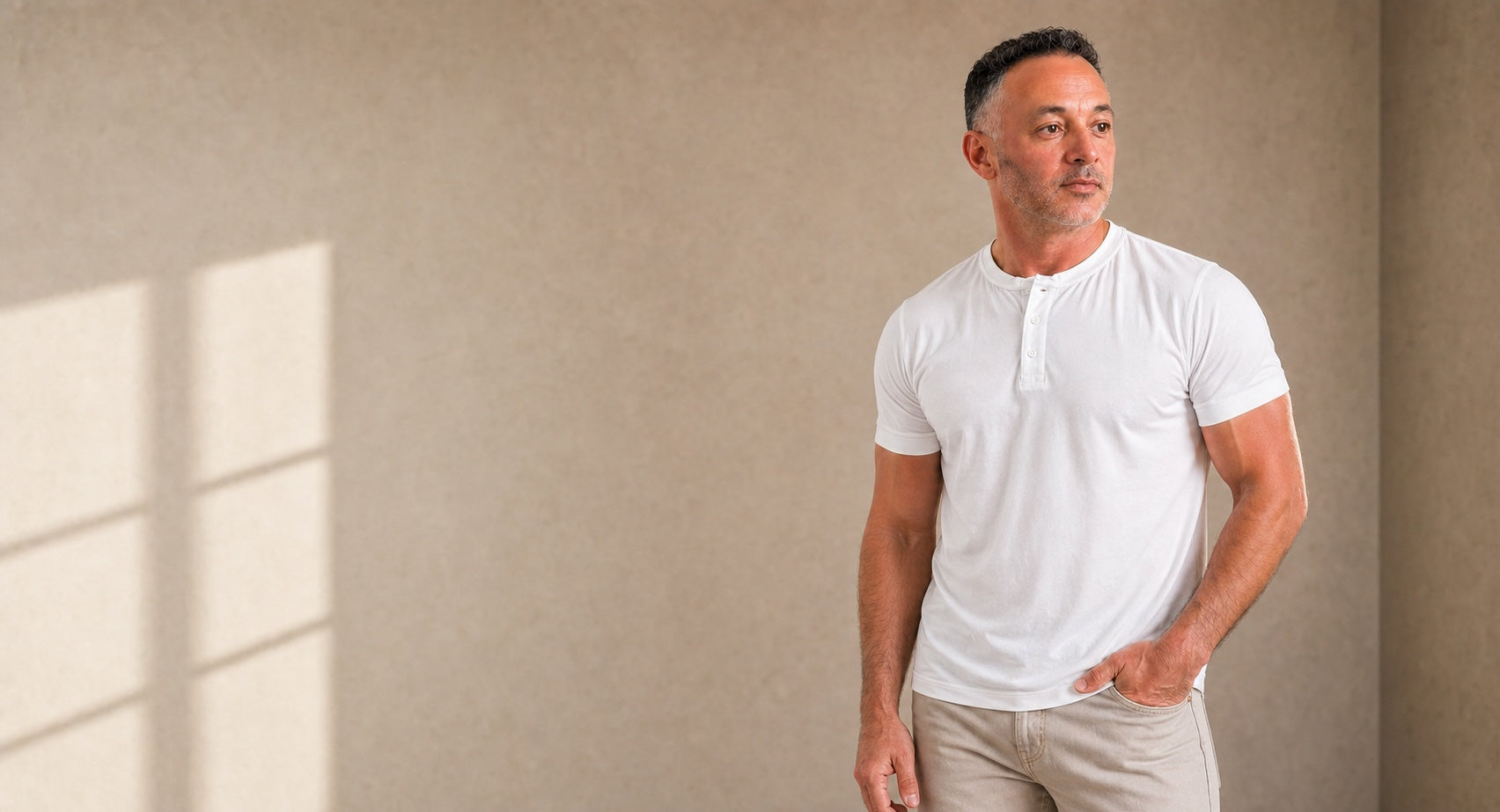 Man wearing a white short-sleeve henley in a warm neutral studio